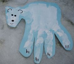 a polar bear shaped paper cutout on the ground next to a snowman's hand