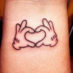 a couple of rabbits holding hands in the shape of a heart tattoo on someone's wrist