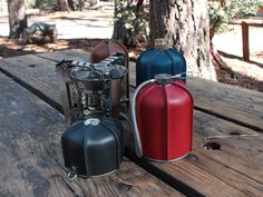 three different colored leather cases sitting on top of a wooden table next to a tree