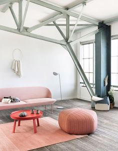 a living room filled with furniture and a pink ottoman sitting on top of a wooden floor