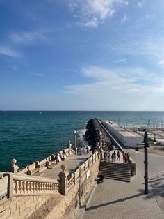 people are walking along the boardwalk by the water