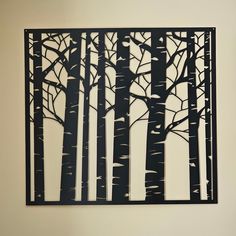 a metal wall hanging with trees cut out of it's sides in black and white