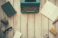 an old fashioned typewriter sitting on top of a wooden table next to other items