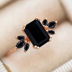 a black stone ring sitting on top of a white cushion