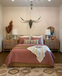 a bedroom with a bed, two nightstands and a cow skull on the wall