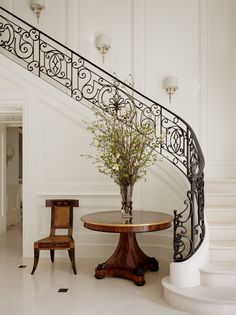 a table and chair sitting under a stair case in a room with white painted walls