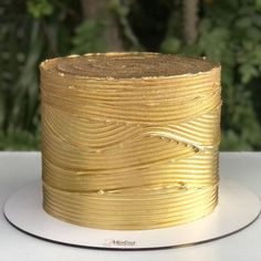 a roll of gold ribbon sitting on top of a white plate with trees in the background