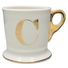 a white and gold coffee cup on a saucer with a golden trim around the edge