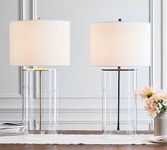 two lamps sitting on top of a table next to a vase with flowers in it