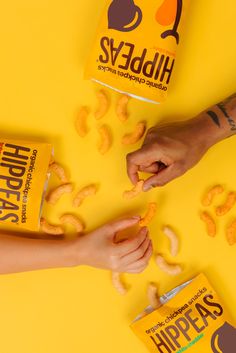 two people reaching for some food on a yellow surface with the help of their hands