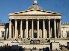 people are sitting on the steps in front of an old building with columns and pillars