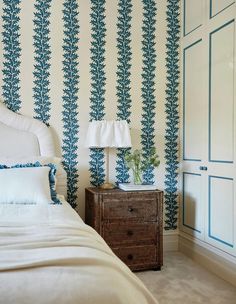 a bedroom with blue and white wallpaper and a bed in front of a dresser