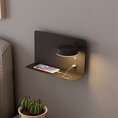 an electronic device is plugged into the side of a wall mounted shelf next to a potted plant