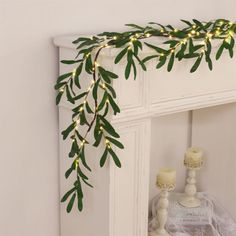 a white mantle with candles and greenery on it