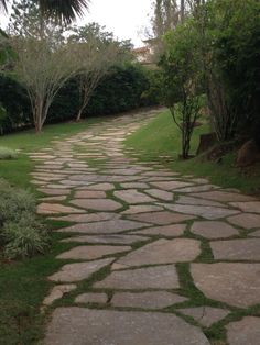 a stone path in the middle of a lush green park