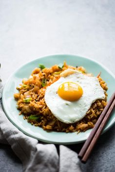 fried rice with an egg on top and chopsticks next to it in a blue plate