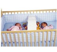 two babies laying in crib next to each other