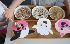 two children are eating cereal from bowls and spoons in front of their food tray