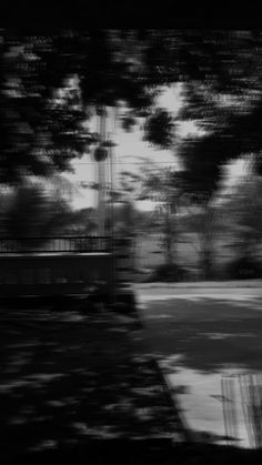 a black and white photo of a park with trees in the foreground, blurry