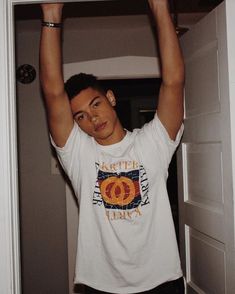 a young man is holding his arms up in the air while wearing a white shirt