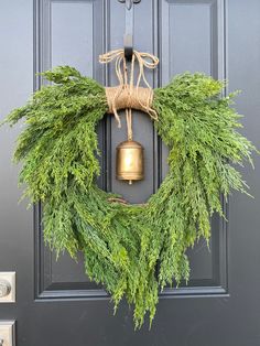 a wreath with a bell hanging on the front door