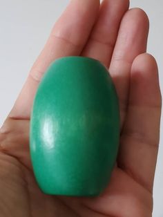 a hand holding an egg in it's palm, with the top half painted green