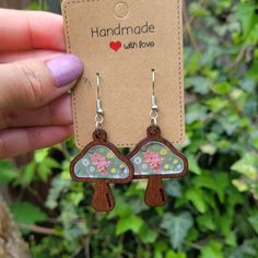 a pair of wooden earrings with flowers on them are being held up by a hand