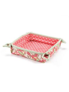 a pink and white polka dotty tray with handles on the bottom, sitting on a white surface