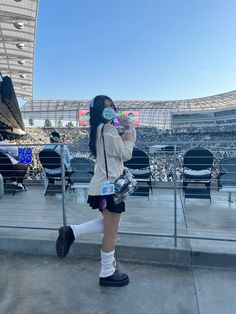 a woman in white shirt and black shorts standing next to a metal fence at a stadium