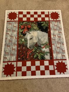 a white horse in a christmas wreath on a red and white quilt