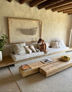 a woman sitting on a white couch in a living room next to a coffee table