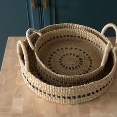 two woven baskets sitting on top of a wooden table