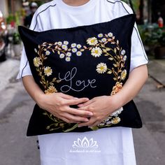 a person holding a pillow with the word love written on it