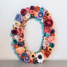 the letter o is made out of flowers and has an oval shape with many different colors