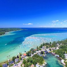 an aerial view of a small town and the ocean with boats in the blue water