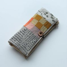 a small wallet is decorated with multi - colored squares and circles, on a white surface