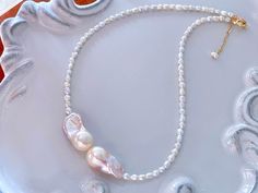 Introducing our Pink Baroque Necklace, a whimsical and enchanting piece that captures the beauty of nature. This necklace features unique baroque pearls in a lovely shade of pink, reminiscent of delicate kissing fish. The 14k gold filled necklace adds a touch of luxury and elegance to the design. This necklace makes a perfect gift for her, be it for a birthday, anniversary, or any special occasion. The pink baroque pearls are also associated with the birthstone of certain months, making it an id Unique Pearl White Necklace As Gift, Unique Pearl White Necklace For Gift, Whimsical Pearl Charm Jewelry As Gift, Whimsical Pearl Charm Jewelry For Gifts, Whimsical White Pearl Jewelry, Whimsical White Wedding Necklaces, Gold Whimsical Jewelry With Unique Variations, Baroque Necklace, Pink Baroque