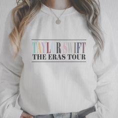 a woman with long hair wearing a white sweatshirt that says tail rout the eras tour