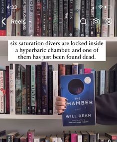 a person holding up a book in front of a bookshelf filled with books