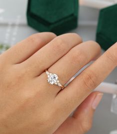 a woman's hand holding an engagement ring with three stones on it and two diamonds in the middle