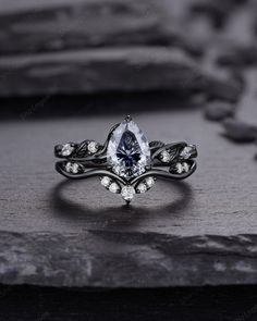 an engagement ring with a pear shaped blue diamond surrounded by white diamonds on top of a stone