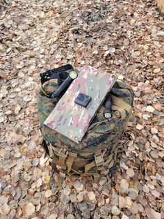 a camouflaged backpack sitting on top of a pile of rocks