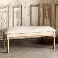 an old wooden bed sitting in front of a wall with peeling paint on the walls