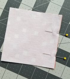 a piece of fabric with pins sticking out of it next to some sewing needles and thread