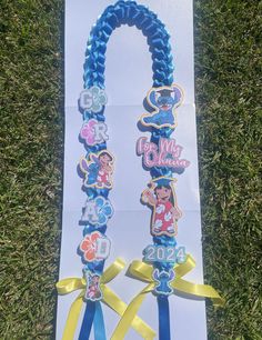 a blue and yellow lanyard with mickey mouse charms on it's side in the grass