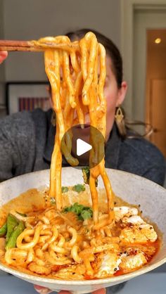 someone is holding up noodles with chopsticks to eat it in front of the camera