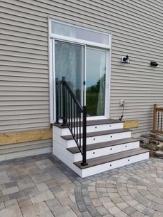 the front steps are made of concrete and have black railings on each handrail