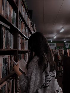 a woman standing in front of a bookshelf filled with lots of book shelves