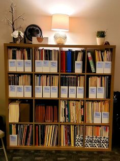 a bookshelf filled with lots of books next to a lamp on top of a table