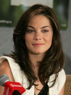 a woman with long hair sitting in front of a microphone and looking at the camera